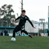 Football player in action during outdoor match in modern sportswear.