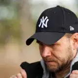 Close-up portrait of a man in a black New York Yankees cap outdoors, focusing on his face.