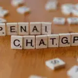 Wooden letter tiles spelling 'OPENAI CHATGPT' on a wooden surface, focused image.