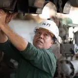 Engineer examines heavy machinery in an industrial site, showcasing technical expertise.