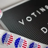 I Voted stickers with an American flag design and Voting Day sign symbolize U.S. electoral participation.
