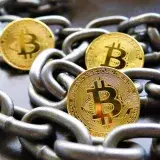 Close-up of Bitcoin coins entwined in metallic chains showcasing cryptocurrency security.