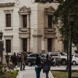 People walking on a street in Mérida, Venezuela, featuring historic architecture and parked cars.