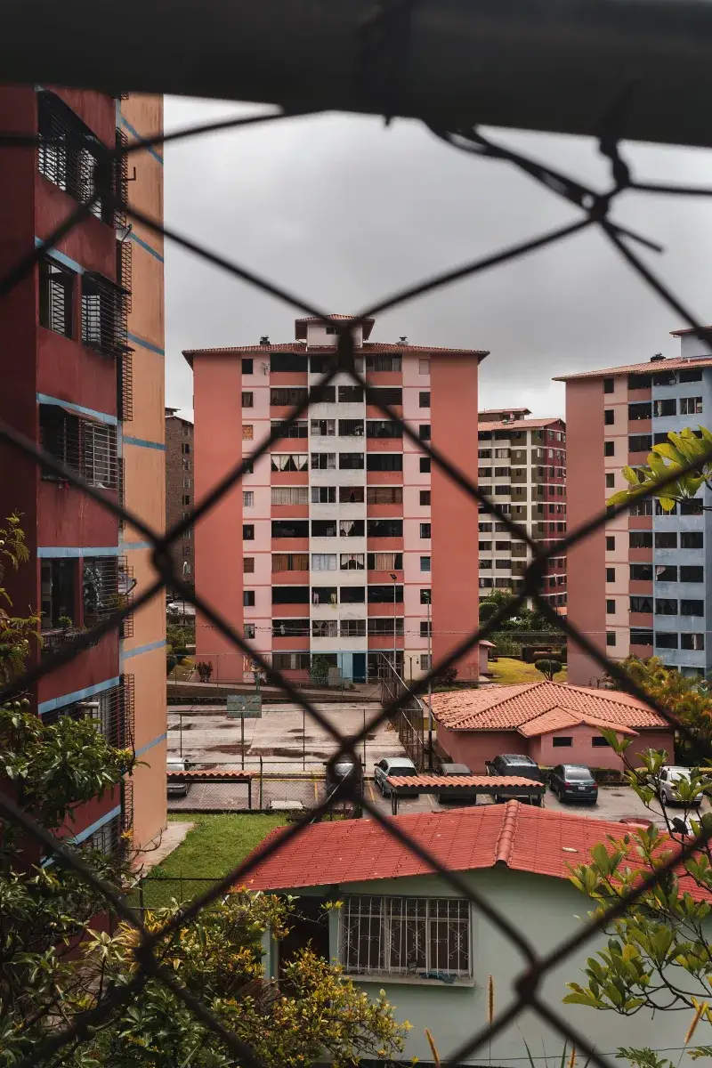 Chain link fence framing modern residential buildings in Mérida, Venezuela.
