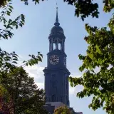 Gothic architecture of St. Michael's Church tower framed by trees in Hamburg, Germany.