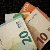 Close-up of euro banknotes and credit cards on a dark textured surface.