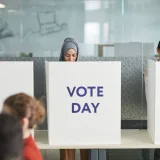 Two women casting their votes in an office during election day, focusing on diversity and civic engagement.