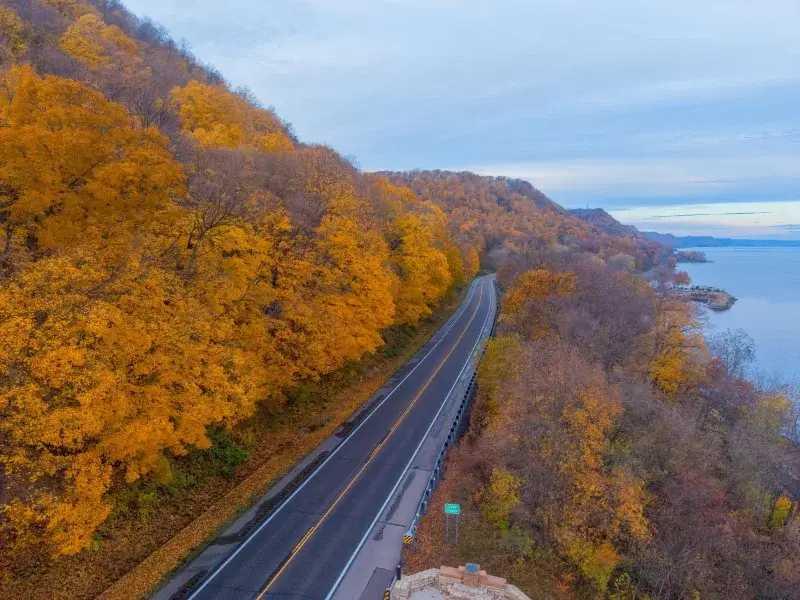 Aerial view of a vibrant autumn landscape along a winding road in Reads Landing, Minnesota by the Mississippi River.