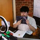 Man analyzing cryptocurrency data with ring light and flip charts in a home office.