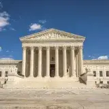 The majestic facade of the United States Supreme Court under a clear blue sky.