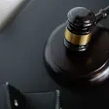 From above of wooden gavel on round surface near folders on table in courtroom