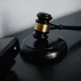 High angle of shiny wooden ceremonial mallet with golden detail placed on judge tale near documents folders