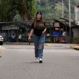 Woman walking in urban Venezuela, showcasing casual street style with beanie and ripped jeans.