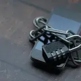 Close-up of a smartphone wrapped in a chain with a padlock, symbolizing strong security.