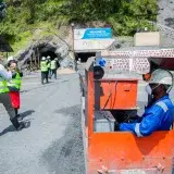 Workers at an outdoor mining site with a focus on rail transport safety.