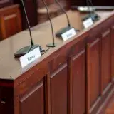 Empty courtroom desk with microphones and nameplates in a Polish court setting.