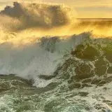Powerful ocean waves crashing at sunset in Porto, Portugal, capturing nature's raw beauty.