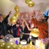 Vibrant birthday party with friends celebrating amidst balloons and festive decorations.