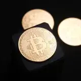Close-up of golden Bitcoin coins on a sleek black background, emphasizing cryptocurrency themes.