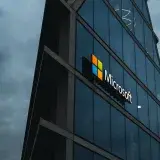 A modern Microsoft office skyscraper with glass facade against a cloudy evening sky.