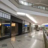 Spacious and contemporary mall interior with closed stores and escalator.