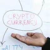 Close-up of a hand gesturing at a cryptocurrency diagram on a whiteboard, highlighting crypto concepts.
