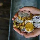 A close-up of hands holding various cryptocurrency coins, representing digital finance.