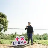 Woman smiling and posing by a sign at Lerma Lake, Santa María Atarasquillo, México.