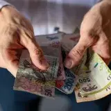 Closeup of hands holding various Argentine peso banknotes, depicting economic and financial concepts.