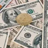 Bitcoin coin placed on scattered US dollar bills, representing cryptocurrency and finance.