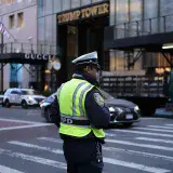 NYPD officer managing traffic outside Trump Tower on a busy New York City street.