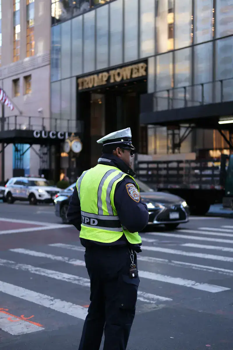 NYPD officer managing traffic outside Trump Tower on a busy New York City street.
