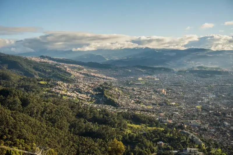 Aerial shot of Bogotá, Colombia, showcasing cityscape and surrounding lush mountains.