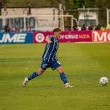 Foto dinámica de un jugador de fútbol pateando la pelota durante un partido.