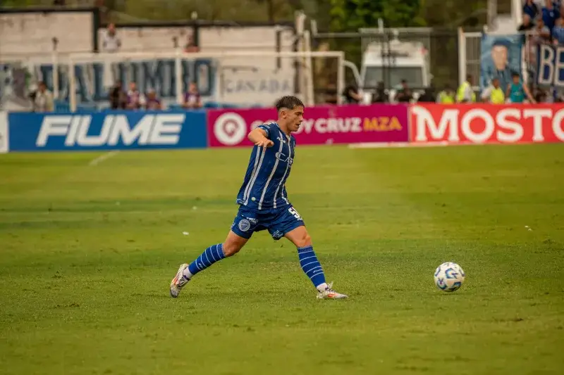 Foto dinámica de un jugador de fútbol pateando la pelota durante un partido.