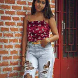 Teenage girl wearing trendy outfit in Venezuela, posing confidently by a rustic red door.