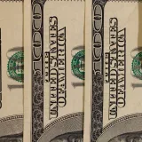 Detailed close-up of multiple US hundred dollar bills, showcasing currency design.