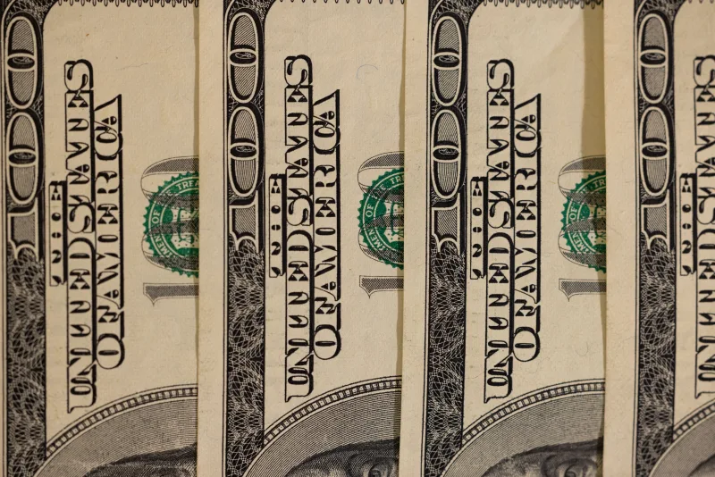 Detailed close-up of multiple US hundred dollar bills, showcasing currency design.