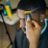 A barber trims a man's hair with precision using clippers in a salon.