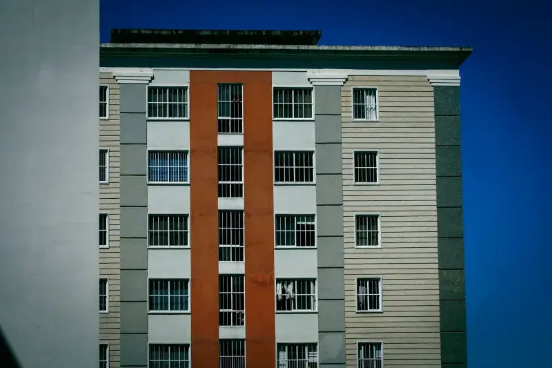 Facade of a modern high-rise building with colorful design against a clear blue sky.