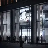 Illuminated Apple Storefront with people outside at night in Hamburg, Germany.