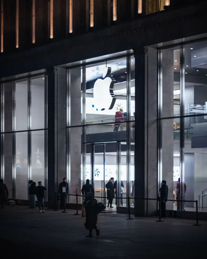 Illuminated Apple Storefront with people outside at night in Hamburg, Germany.