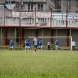 Amateur soccer players compete on an urban field in Venezuela, showcasing teamwork and athleticism.