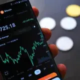 Close-up of Bitcoin trading app on smartphone showing market trends and digital coins.