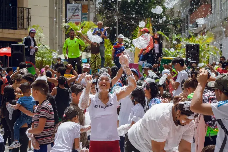 People enjoying a lively foam festival on a sunny day in Venezuela. Vibrant community celebration.