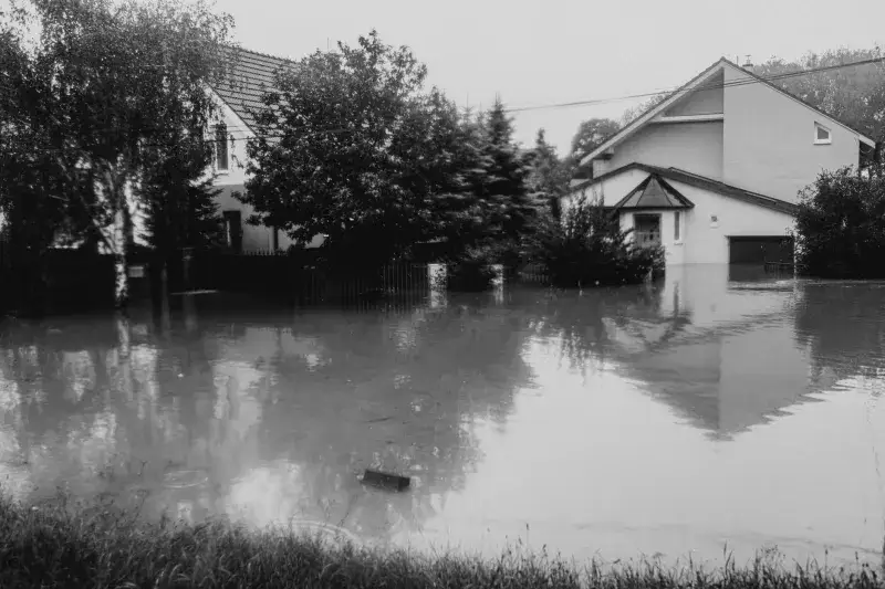 Black and white photo of suburban street flooded, houses submerged in water.