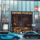 Dynamic view of Trump Tower's entrance with bustling street traffic in New York City.