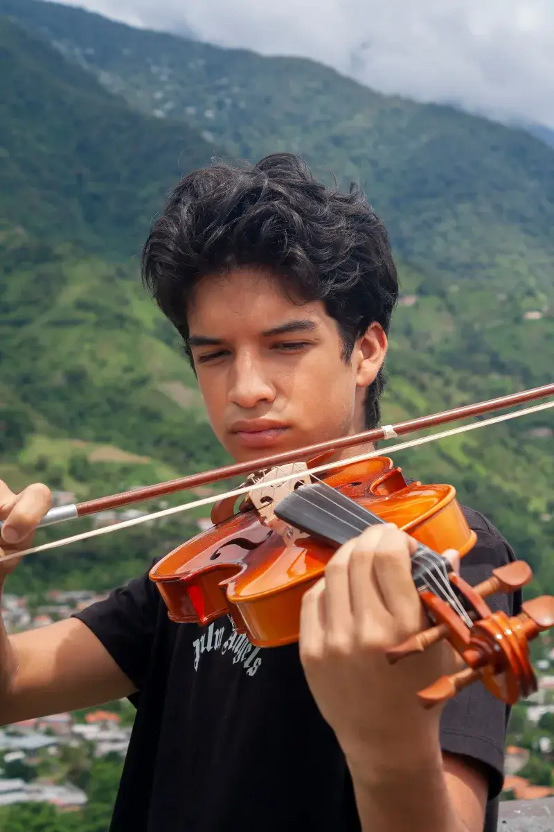 Portrait of a young violinist performing amidst the lush landscape of Mérida, Venezuela.