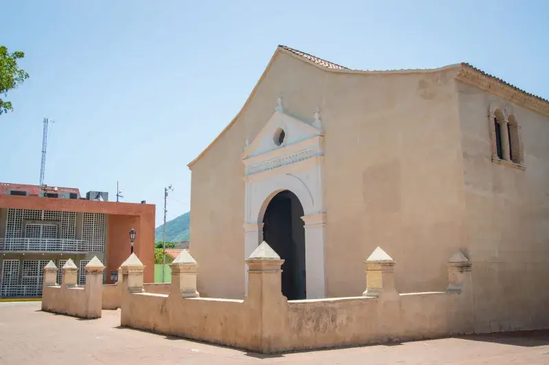 A side view of La Asuncion Cathedral, a historic landmark in Venezuela, under a clear sky.