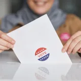 Close-up of hands holding a vote ballot, symbolizing election participation.